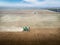 Aerial pair of John Deere combines harvesting a wheat field with dust trails