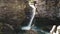 Aerial pan of amazing secret waterfall carving through rocks in gorge