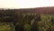 An aerial panning shot of a golf course nestled in an evergreen forest with golfers playing on the fairways and greens