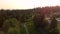 An aerial panning shot of a golf course nestled in an evergreen forest with golfers playing on the fairways and greens