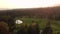 An aerial panning shot of a golf course nestled in an evergreen forest with golfers playing on the fairways and greens