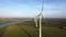 Aerial panning shot of rotating wind turbines in a Dutch landscape.