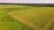 Aerial panorama of agricultural land, a combine is working in the distance.