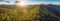 Aerial panorama of beautiful Australian Alps at sunset. Forested hills and rural road.