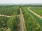 Aerial panorama of the road, that leads between green patterns of fields and gardens