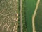 Aerial panorama of the road, that leads between green patterns of fields and gardens