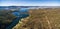 Aerial panorama of Snowy River flowing among green hills of Australian Alps and lake Jindabyne