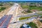 Aerial panorama top down view of an unfinished asphalt covered road with dirt, tracks of heavy machinery at construction site. The