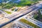 Aerial panorama top down view of an unfinished asphalt covered road with dirt, tracks of heavy machinery at construction site. The