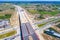 Aerial panorama top down view of an unfinished asphalt covered road with dirt, tracks of heavy machinery at construction site. The