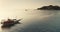 Aerial panorama: two yachts sailing near tropical island. Sunset sun reflect in calm sea water