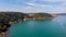 An aerial panorama view of a beautiful bay with calm blue water surrounded by forest under a majestic blue sky and some white