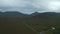 Aerial panoramic footage of landscape with mountains in background. Stream winding along straight road. Ireland