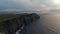 Aerial panoramic footage of sea coast with high cliffs. Waves rolling to shore. Cliffs of Moher, Ireland