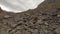 Aerial panoramic view active traveler backpacker women climbing to mountain peak on cliff stones terrain under cloudy