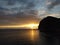 Aerial panoramic view of beautiful sunset above calm azure sea and volcanic rocky shores. Sun glare, small waves on the
