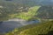 Aerial panoramic view of Bohinj Lake with mountain range and valley with small village.