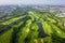 Aerial panoramic view drone shot of beautiful golf course with people playing golf in field and houses in city