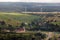 aerial panoramic view of green village with houses, barns and gravel road in forest with windmills