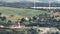 aerial panoramic view of green village with windmills on hill