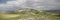 Aerial panoramic view of lush green Monte Ocre against dark cloudy sky in Apennines Italy