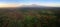 Aerial, panoramic view on Mount Kilimanjaro volcano, summit covered in snow lit by first sun rays with masai villages with