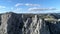 Aerial panoramic view of mountain cableway, above green trees on blue, cloudy sky background. Shot. Fascinating cliffs