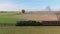 Aerial Parallel View of a Steam Train Traveling Behind Trees as it Travels Thru Farmlands