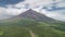 Aerial of Philippines volcano peak eruption clouds haze. Hiking path at hillside green grass valley