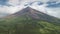 Aerial of Philippines volcano peak eruption clouds haze. Hiking path at hillside green grass valley