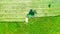 Aerial photo farm scene agricultural tractor mows grass with a mower in the farm fields, haymaking