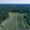 Aerial photograph of a rectangular, arable land between woods and a dead straight asphalted country road from greater height,