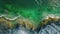 An aerial photograph showcasing a rocky beach with vibrant green water, Aerial panorama of an emerald sea lapping against stony