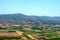 Aerial photography. View from the plane`s window: mountains on the horizon, green fields and meadows below.