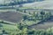 Aerial with ploughed fields and rural building in hilly countryside around Montepulciano historical town, Siena, Italy