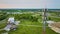 Aerial radio tower, grass field, distant houses housing homes neighborhood, small forest