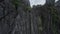 Aerial raising view wild island cliff formation covered by tropical plant rock texture sea ocean landscape