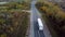 Aerial rear side view of semi truck moving along a highway with cargo trailer.