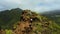 Aerial rear view woman hiking climbs crawling the edge of a cliff in mountain landscape. Tourist enjoys natural volcanic