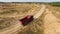 Aerial for the red big truck driving in ground quarry with flying dust behind it, industry concept. Scene. Empty lorry