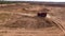 Aerial for the red big truck driving in ground quarry with flying dust behind it, industry concept. Scene. Empty lorry