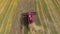 Aerial of red combine harvester working on large wheat field