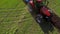 Aerial of red tractor plowing soil on green agricultural field