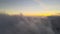 Aerial reveal shot from above at high altitude of dense puffy cumulus clouds flying in evening. Amazing sunset from