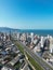 Aerial of road with cars, urban buildings by Meia Praia beach in Itapema City in Brazil