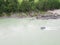 Aerial of a rubber motor boat sailing on a green river in the mountains between rocks and cliff