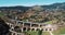 AERIAL Scenic shot from above of an idyllic rural town under the colorful mountains and the railway viaduct