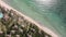 Aerial scenic view of sea waves, green palms, hotels, houses and resorts on the sandy beach.