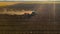 Aerial shot of agricultural field with tractor pulling a disc harrow over agricultural field, farmland