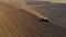 Aerial shot of agricultural field with tractor pulling a disc harrow over agricultural field, farmland